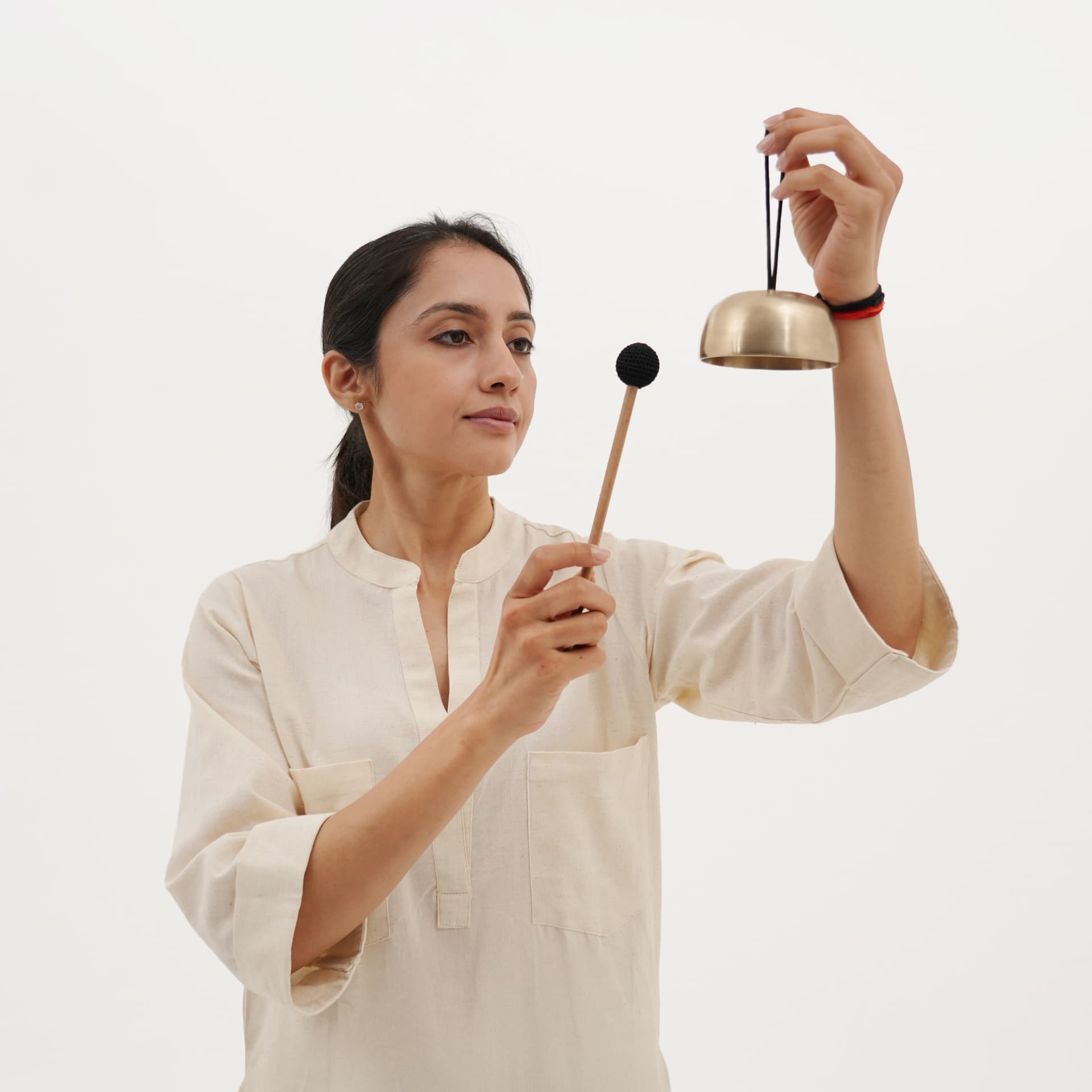 A practitioner holding the Mindfulness Bell and mallet in soft natural light.